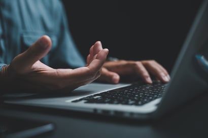 Mains au-dessus du clavier d'un ordinateur portable dans la pénombre