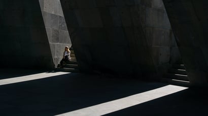 Femme assise dans un rai de lumière entre de hauts murs de pierre sombres